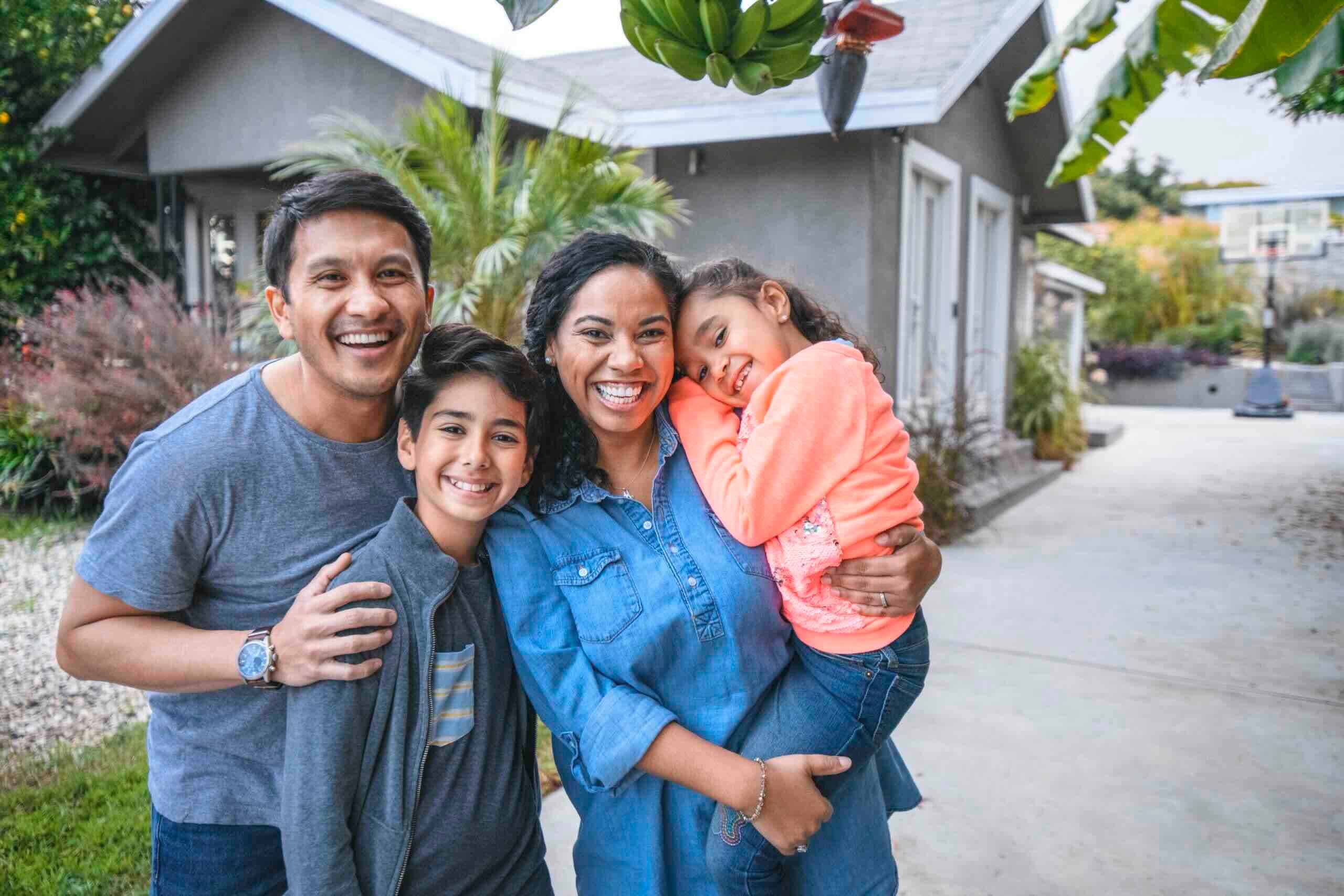 A smiling and happy young family in front of their new home.